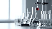 Laboratory glassware and equipment on white table in modern research facility with natural window lighting for scientific experiments and analysis.