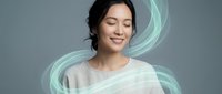 Young Asian woman with closed eyes surrounded by flowing mint green energy waves on gray background for wellness and meditation concepts.