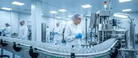 Pharmaceutical worker in sterile cleanroom operating automated production line with glass vials. Modern medical manufacturing facility with quality control.