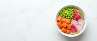 Fresh poke bowl with salmon, edamame, radish, and watermelon radish on white marble background, top view with copy space.