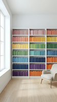 Modern home library with rainbow colored books organized by hue in white built-in shelving unit creating vibrant wall display in minimalist reading room.