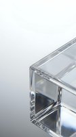 Clear crystal glass cube with prismatic light reflections creating rainbow spectrum effects on white background for modern design projects.