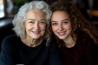 Senior woman with silver curly hair and young female with natural curls sharing genuine smiles in close portrait, representing family bond and generational connection.