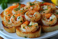 Garlic shrimp bruschetta appetizers garnished with fresh herbs and seasonings on toasted baguette slices, served on white plate. Close up view of seafood starter.