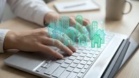 Professional woman typing on laptop with holographic smart home technology icons floating above keyboard for digital property management solutions.