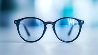Modern round eyeglasses with black frame on blurred blue background, stylish optical accessory for vision correction and fashion statement.