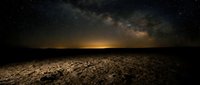 Vast desert landscape under starry night sky with glowing milky way galaxy stretching across horizon, golden light on sandy terrain, astronomy and nature background.