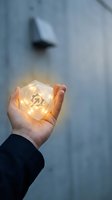 Hand holding illuminated geometric crystal with glowing symbol against blurred urban background, representing innovation, energy, and spiritual growth for business and wellness concepts.