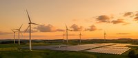 Wind turbines and solar panels generating renewable energy at sunset with golden sky and clouds creating sustainable power landscape for environmental projects.