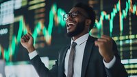 Young African American businessman celebrating success in front of glowing green stock market charts, wearing suit and glasses, expressing joy and achievement.