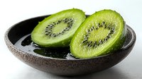 Fresh juicy kiwi fruit sliced in half showing seeds and bright green flesh in brown ceramic bowl with water drops on white background. Food photography.