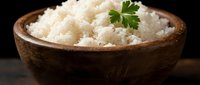 Steamed white rice in rustic wooden bowl garnished with fresh parsley on dark background for healthy meal preparation and cooking content.
