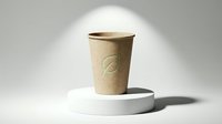 Kraft paper takeaway cup with embossed logo on white cylindrical podium against neutral background, suitable for beverage packaging mockups and cafe branding.