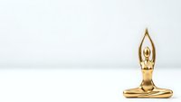 Golden yoga meditation figurine in lotus pose on white background for wellness and mindfulness design projects.