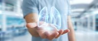 Healthcare professional holding glowing digital lungs hologram in modern medical facility for respiratory health technology and pulmonology concepts.