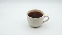 Cream ceramic mug filled with dark coffee or tea beverage, isolated on white background, ready for beverage, cafe, and kitchen design projects.