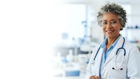 Confident African American female doctor with stethoscope smiling in modern hospital setting with medical equipment background for healthcare concepts.