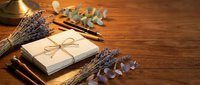 Wrapped gift box with twine bow surrounded by dried lavender bundles and eucalyptus leaves on wooden surface, suitable for holiday, celebration, and gift-giving concepts.