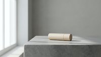 Minimalist wooden cylinder object on concrete surface near window with natural light creating soft shadows in modern interior space.