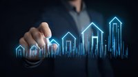 Businessman pointing at glowing blue house icons showing rising real estate market trend graph on dark background, representing property investment growth.