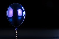 Shiny metallic blue balloon floating against dark background with dramatic lighting and reflection creates mysterious celebratory atmosphere.