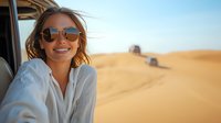 Young Caucasian woman with sunglasses smiling while traveling in desert safari vehicle, wind blowing through hair against golden sand dunes background on sunny day.
