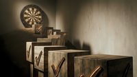 Wooden boxes stacked with checkmarks and dartboard on wall, representing business success, goal achievement, and project completion for corporate presentations.
