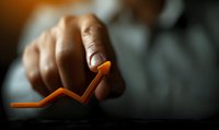 African American businessman pointing at orange upward trending graph line showing business growth and success on dark background with selective focus.