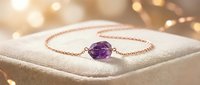 Delicate rose gold chain bracelet featuring a polished amethyst gemstone centerpiece, displayed on cream fabric with warm bokeh lighting for jewelry retail and luxury accessory marketing.