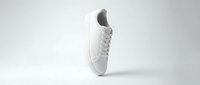 Clean white lace-up sneaker floating on a light gray background, showcasing minimalist casual footwear design for fashion and lifestyle branding.