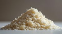 Fresh grated parmesan cheese pile on white surface, culinary ingredient for cooking and food preparation in kitchen.