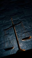 Golden scales of justice with dramatic lighting against dark textured background for legal and law firm concepts.