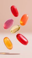 Colorful vitamin supplements or medicine capsules floating in air against soft pink background. Levitating pills showcase pharmaceutical or healthcare concept.