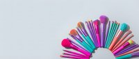 Colorful makeup brushes arranged in semicircle on white background. Professional cosmetic tools for beauty application isolated for design use.