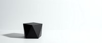 Black geometric cube with angular faceted surfaces casting shadow on white background, suitable for modern design, architecture, and minimalist concepts.