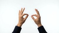 Two hands making OK gesture sign with fingers forming circles against white background for business communication and approval concepts.