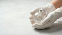 Hands in white gloves holding glass sphere with small plant sprout inside symbolizing environmental protection and growth concept for sustainability.