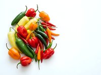 Colorful assortment of fresh bell peppers and hot chili peppers arranged on white background, suitable for food, cooking, nutrition and culinary design projects.