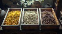 Aromatic dried tea leaves and flowers in rustic wooden boxes, traditional loose leaf tea varieties displayed in vintage serving containers for tea ceremony.