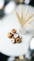 Assorted glazed donuts arranged on white table with pampas grass in crystal vase creating cozy cafe atmosphere for bakery marketing and food photography.