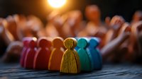Colorful wooden figures arranged in row symbolizing diversity, inclusion and teamwork concept against blurred background with warm lighting effect.