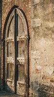 Ancient wooden arched door with metal hardware set in weathered brick and stone wall. Rustic medieval architecture entrance with vintage craftsmanship details.