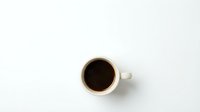 White ceramic coffee cup with black coffee viewed from above on clean white background for morning beverage and cafe design projects.