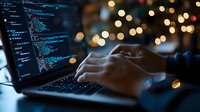 Programmer typing code on laptop with bokeh lights in background, software development workspace.