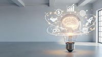 Creative lightbulb with glowing brain and business icons floating in modern office space representing innovation, entrepreneurship and bright ideas.