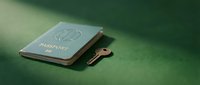 Passport and key on green surface, travel and security concept for tourism, immigration, and journey planning needs.