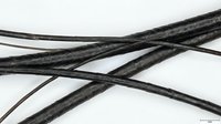 Black leather cords or strings crossed and intertwined on white background, isolated for crafting, jewelry making, and DIY projects.