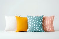 Decorative throw pillows in modern Scandinavian style featuring geometric patterns and pastel colors - white, yellow, mint green, and coral pink arranged in row.