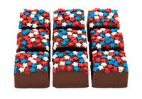 Chocolate brownies topped with red, white, and blue round sprinkles arranged in three rows of three, perfect for patriotic celebrations, bakery displays, and dessert marketing materials.
