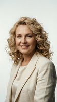 Confident mature businesswoman with curly blonde hair smiling in cream blazer against neutral background for professional corporate headshot photography.